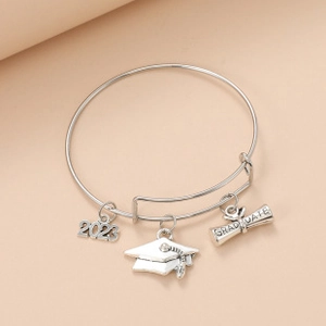 Detail of silver graduate charm bracelet with 2023 number and doctoral cap pendants