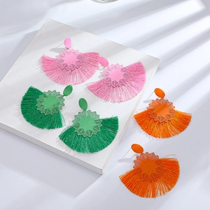 Detalle de pendientes de borla coloridos en tonos rosa, verde y naranja vivo