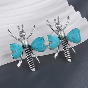 Macro view of vintage silver insect earrings with heart-shaped turquoise stone wings