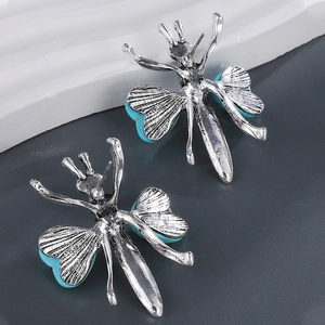 Gros plan de boucles d'oreilles insectes argentées avec des ailes en turquoise