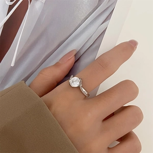 Close-up of classic silver engagement ring with round moissanite on a silk background