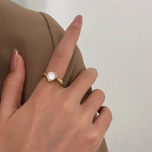 Detailed view of gold twisted band ring with large round solitaire stone worn on finger