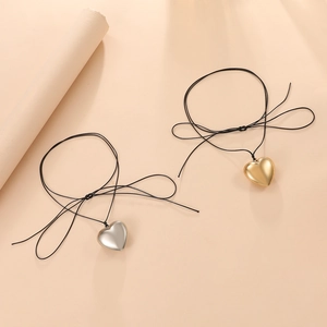 Detail of minimalist gold and silver heart pendants on simple black cord necklaces