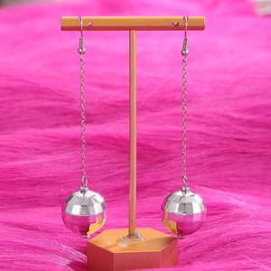 Dettaglio degli orecchini a sfera disco argentati su supporto dorato con sfondo in peluche rosa