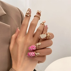 Set de anillos para uñas dorados con circonitas y diseños de mariposa en esmalte rosa