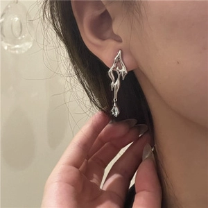 Dettaglio di orecchini asimmetrici in metallo liquido argento con zircone su modella