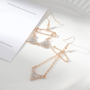Dettaglio di orecchini a forma di bikini dorati con zirconi su vassoio bianco