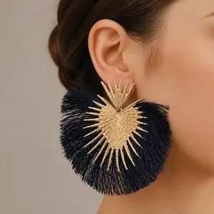 Dettaglio di grandi orecchini a raggiera dorati con nappe in seta blu navy a forma di ventaglio
