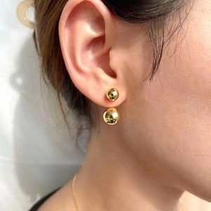Vue détaillée de boucles d'oreilles double boule dorées portées pour un style minimaliste