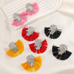 Detail view of colorful fan-shaped tassel earrings on white silk background
