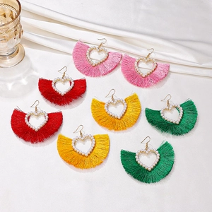 Bohemian heart-shaped earrings with fan-style tassels and pearls on white silk fabric