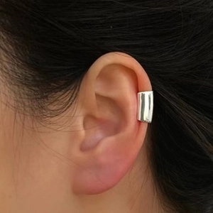Polished silver wide cross ear cuff clip-on jewelry shown in close-up on ear cartilage