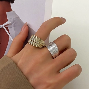 Close-up of gold and silver textured multi-layer rings worn by a model in soft lighting