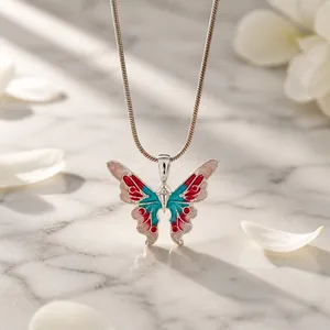 Close-up of butterfly pendant with pink and blue enamel detail on a sleek snake chain