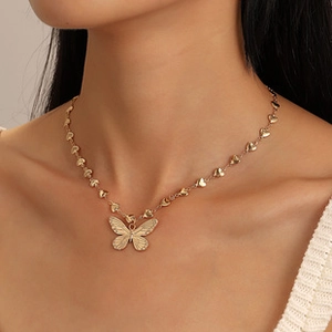 Detailed close-up of golden butterfly pendant with heart-shaped chain links on model neck