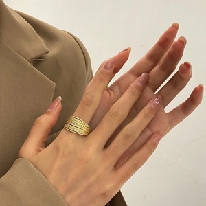 Close-up of trendy gold multi-layer textured stacked ring worn with a blazer