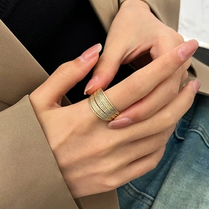 Detailed close-up of a layered wide gold-toned ring with textured multi-strand design