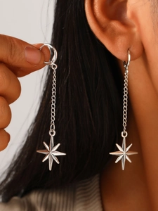 Close-up of silver starburst dangle earrings with chain detail on a model's ear
