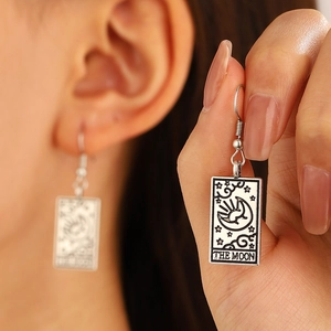 Macro detail of silver tarot earrings featuring 'The Moon' mystical engravings