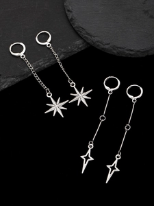 Detailed view of silver gothic star drop earrings on a dark grey stone display