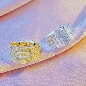 Detail of multi-layer gold and silver rings on silk with textured weave finish