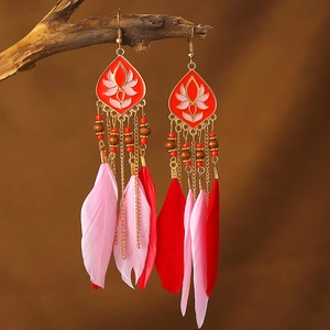 Macro shot of bohemian long earrings with feathers and red beads on a natural wood branch