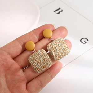 Detailed view of yellow leather-textured stud earrings with blue tweed weave square pendant