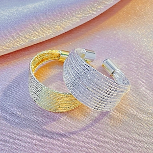 Macro shot of gold and silver multi-layer braided open rings on silk fabric