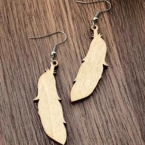 Macro shot of ethnic feather-shaped wooden earrings showing natural grain and silver hooks