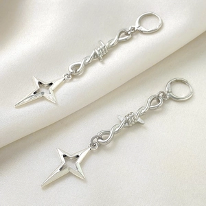 Gothic punk silver thorn star drop earrings on elegant beige silk background
