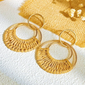 Detail view of bohemian double-loop gold metal earrings with hand-woven raffia textures