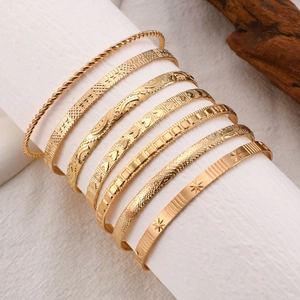 Macro detail of nine-piece gold-plated bracelet set with various textured geometric patterns