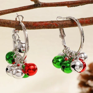 Detailed shot of Christmas bell hoop earrings with red and green charms on a wooden branch