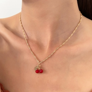 Elegant cherry pendant necklace with red resin fruits and gold twist chain on model