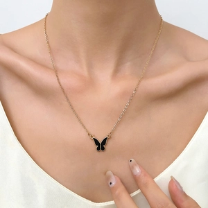 Vista detallada del collar de cadena dorada con colgante de mariposa esmaltada negra