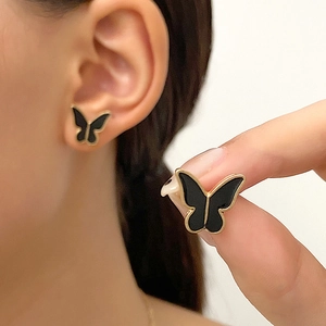 Primer plano de elegantes pendientes de mariposa en oro y negro con acabado esmalte