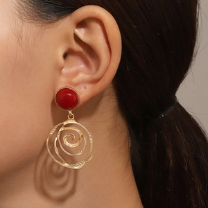 Close-up of vintage hollow gold spiral earrings with red beads on female model