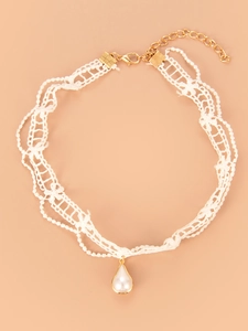 Close-up of white lace choker with teardrop pearl pendant and gold-tone lobster clasp
