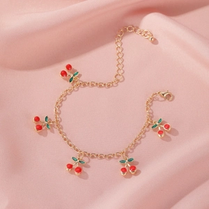 Detail of gold-tone cherry charm bracelet on soft pink silk background with lobster clasp