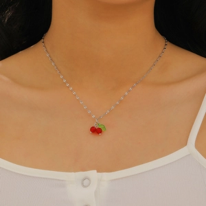 Detailed close-up of a model wearing a cherry pendant necklace with vibrant red beads