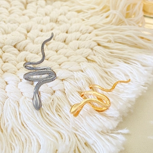 Dettaglio macro degli orecchini a serpente con texture realistiche in oro e argento
