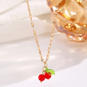Detailed view of cherry pendant necklace with red beads and green leaf on gold chain