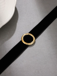 Close-up of black velvet choker featuring a polished gold round metal buckle detail