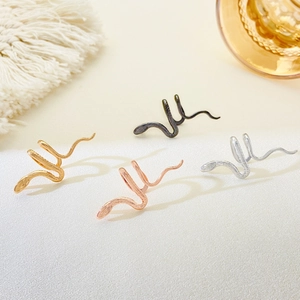 Ear cuff a forma di serpente in oro e argento su tessuto di seta bianca