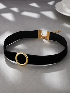 Close-up of gothic velvet choker with golden circle charm and adjustable lobster clasp