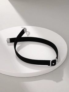 Detail of black velvet choker featuring a silver buckle and adjustable chain on white podium