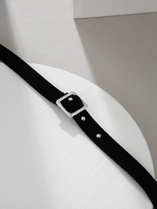 Detail view of black velvet choker featuring a silver square buckle and metal rivets