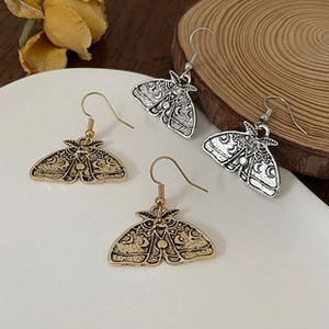 Detail of gothic moth and crescent moon earrings in antique gold and silver finishes