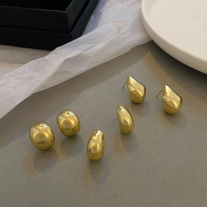 Macro shot of liquid metal gold earrings with organic pebble shapes and glossy finish