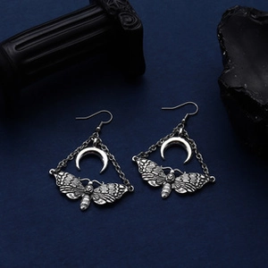 Detail of vintage gothic moth earrings with crescent moon and silver-tone finish